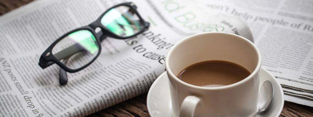 Coffee table with a newspaper, glasses, and a cup of coffee